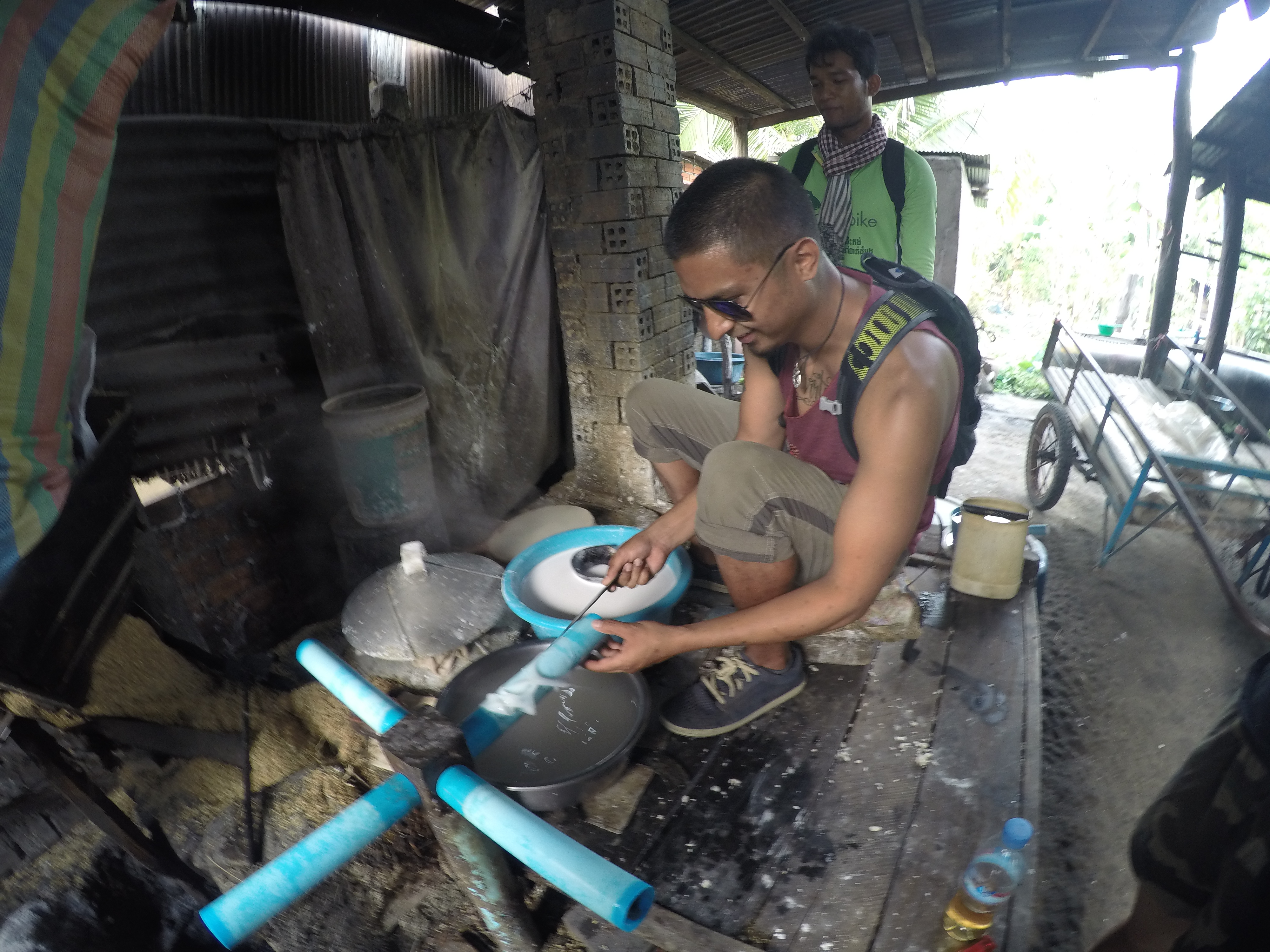 Justin Molina processes a white substance with blue tubes in a rustic Cambodian workshop.