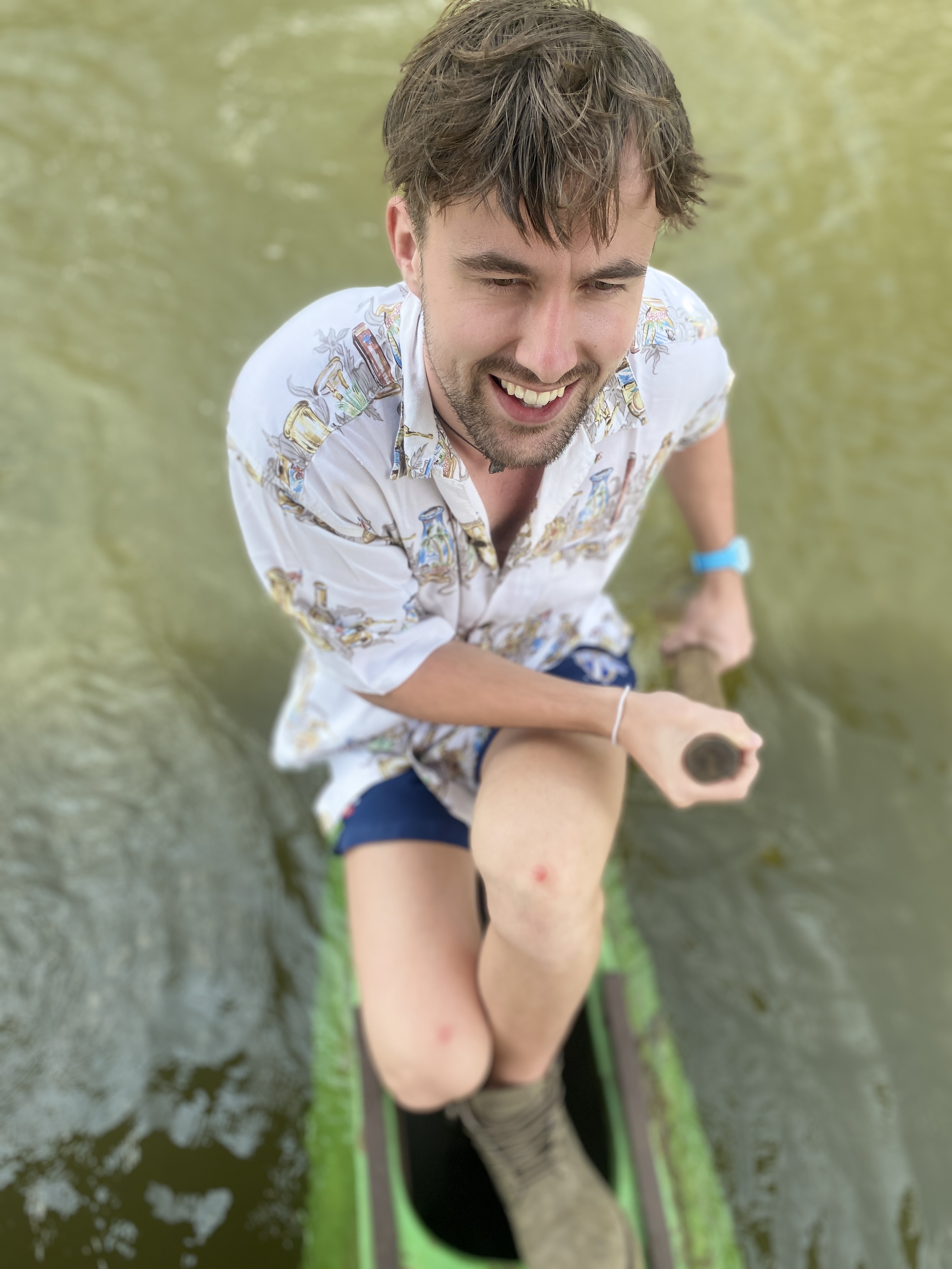 Happy man paddling a green kayak on calm water, enjoying his adventure.