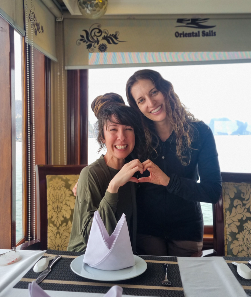 Two smiling women making a heart shape on an Oriental Sails cruise in Ha Long Bay, Vietnam.