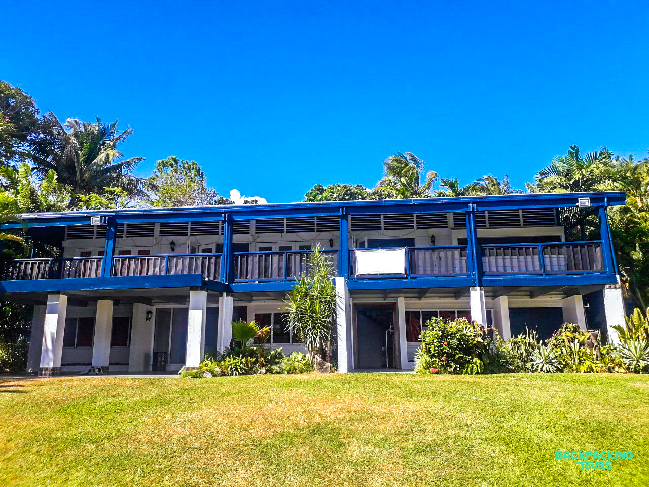 A beautiful two-story accommodation building in Fiji, surrounded by lush green grass and palm trees.