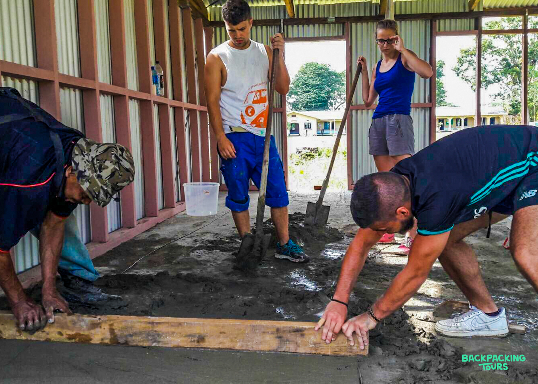 Volunteers work together to level a concrete floor during a renovation project in Fiji.