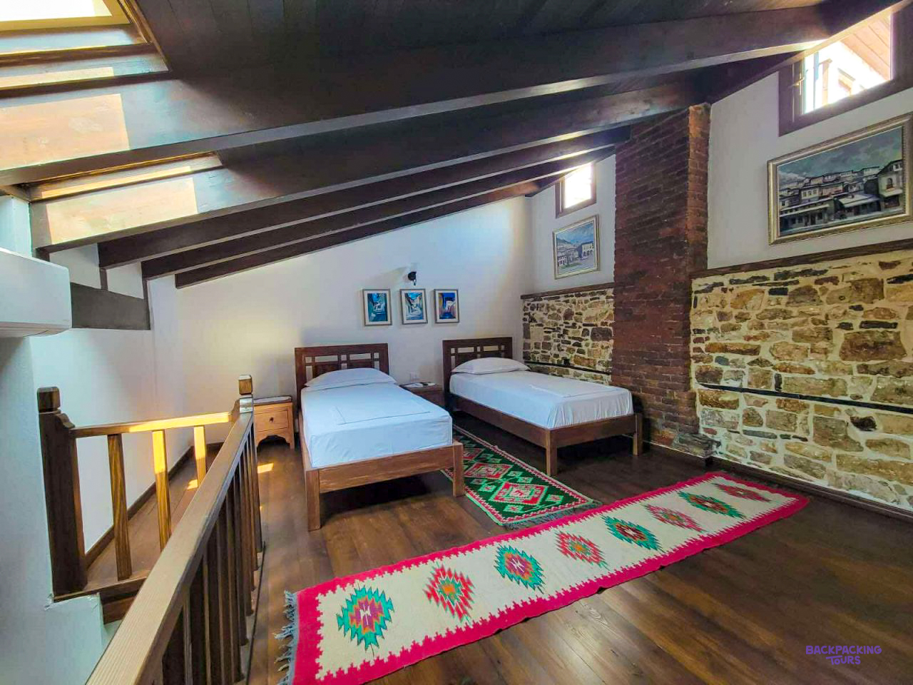 Twin beds and a woven rug in an attic room at the guesthouse in Berat