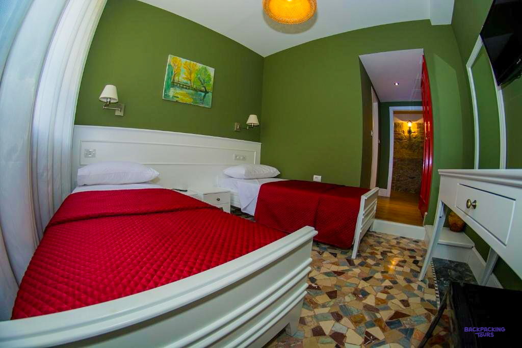 A twin room with red bedspreads and green walls at the hotel in Tirana