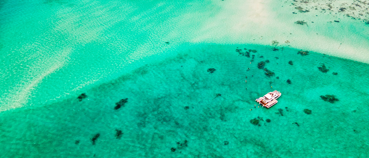 A boat floats on the stunning turquoise waters and coral reefs of Australia's Great Barrier Reef.