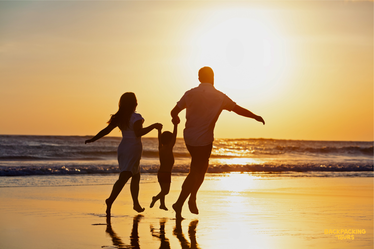 A family runs joyfully along Seminyak beach at sunset, silhouetted against the golden sky.