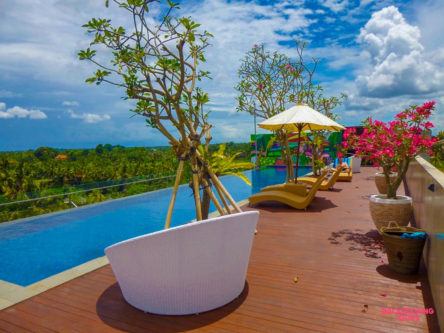 Stunning rooftop infinity pool with stylish white and yellow loungers overlooking the lush Ubud jungle.