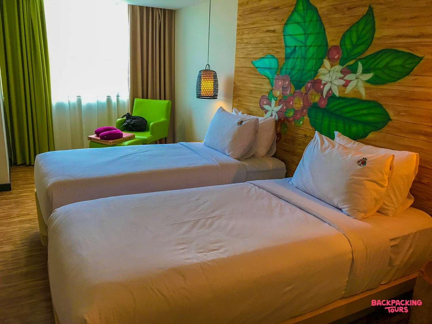 A bright and modern hotel room in Ubud with two comfortable single beds and a tropical mural.