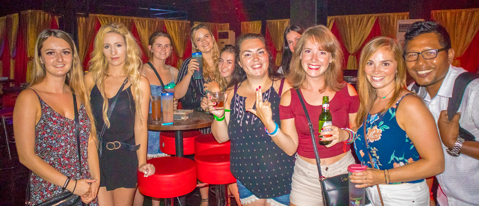Smiling young backpackers enjoying drinks and a night out at a lively bar in Kuta, Bali.