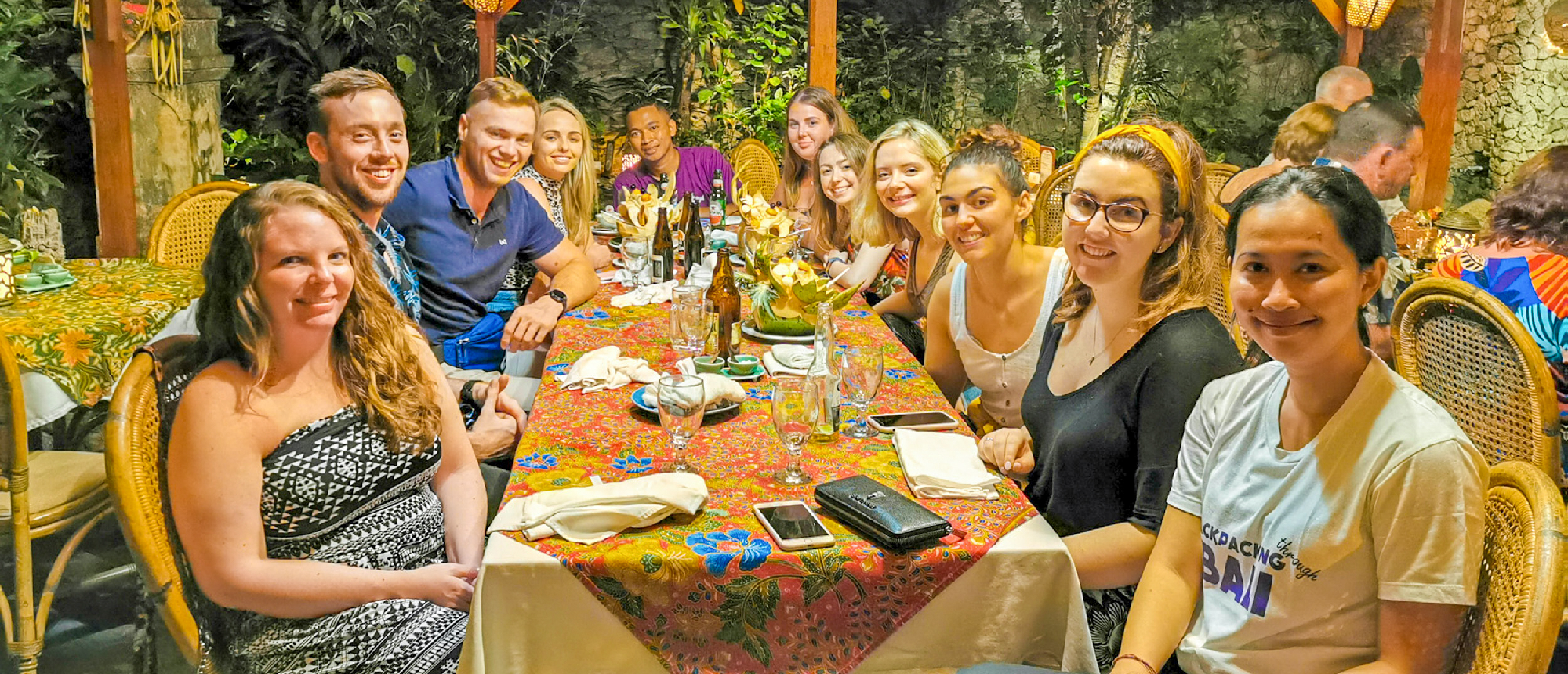A happy group of young travelers enjoying a welcome dinner at a restaurant in Kuta, Bali.
