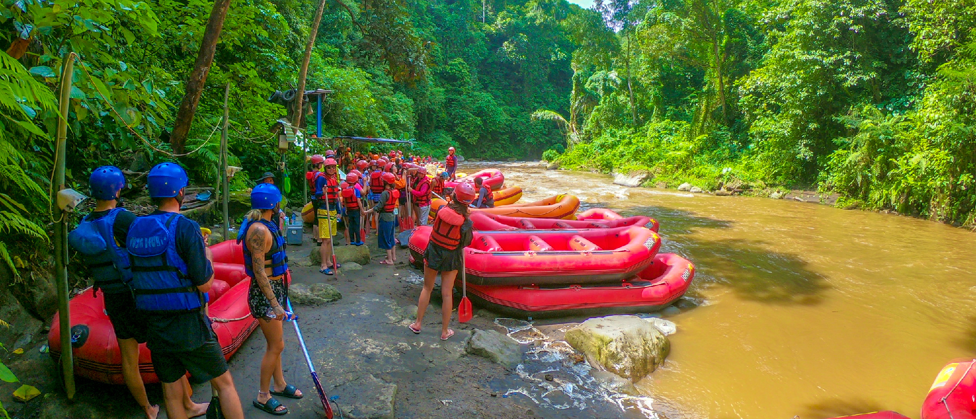 Group of people in life vests and helmets preparing for river rafting in a lush jungle in Ubud, Bali.