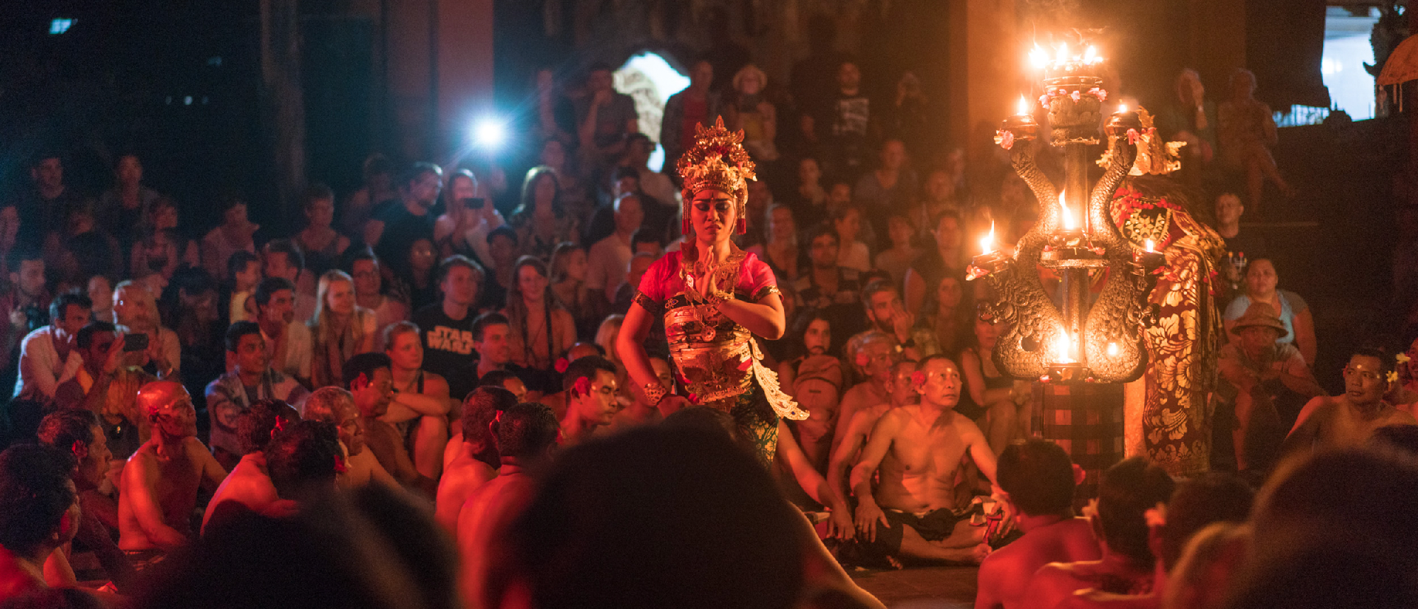 A vibrant Kecak fire dance performance with a main dancer and many onlookers in Ubud, Bali.