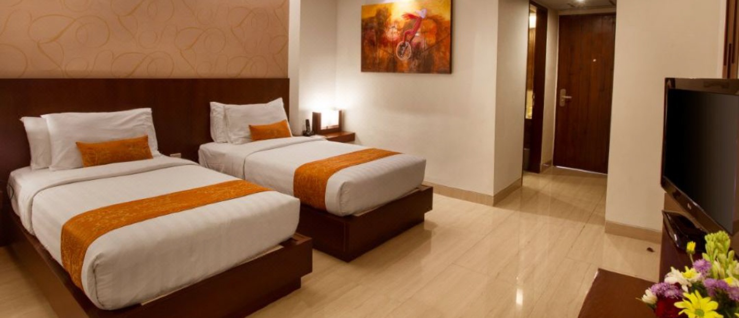 A comfortable hotel room in Seminyak, Bali, with two single beds and modern decor.