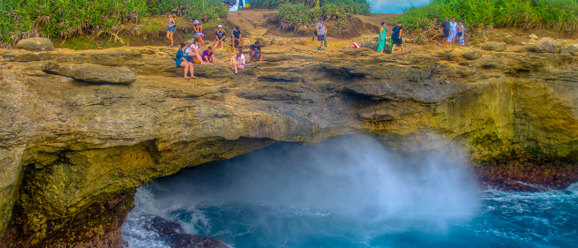 Excited visitors watch a dramatic ocean blowhole spray water high at Devil's Tear, Nusa Lembongan.