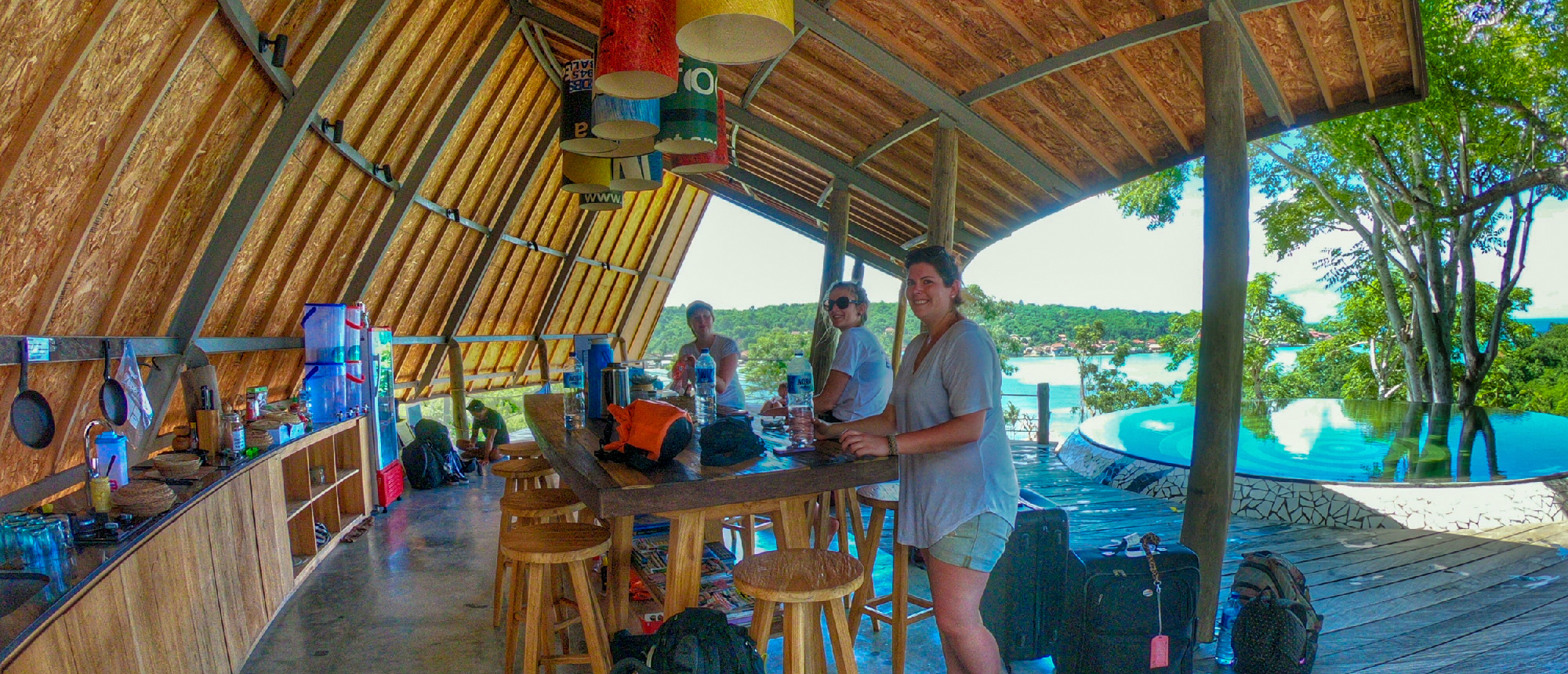 Backpackers relax at a vibrant open-air bar overlooking the stunning coastal view of Nusa Lembongan.
