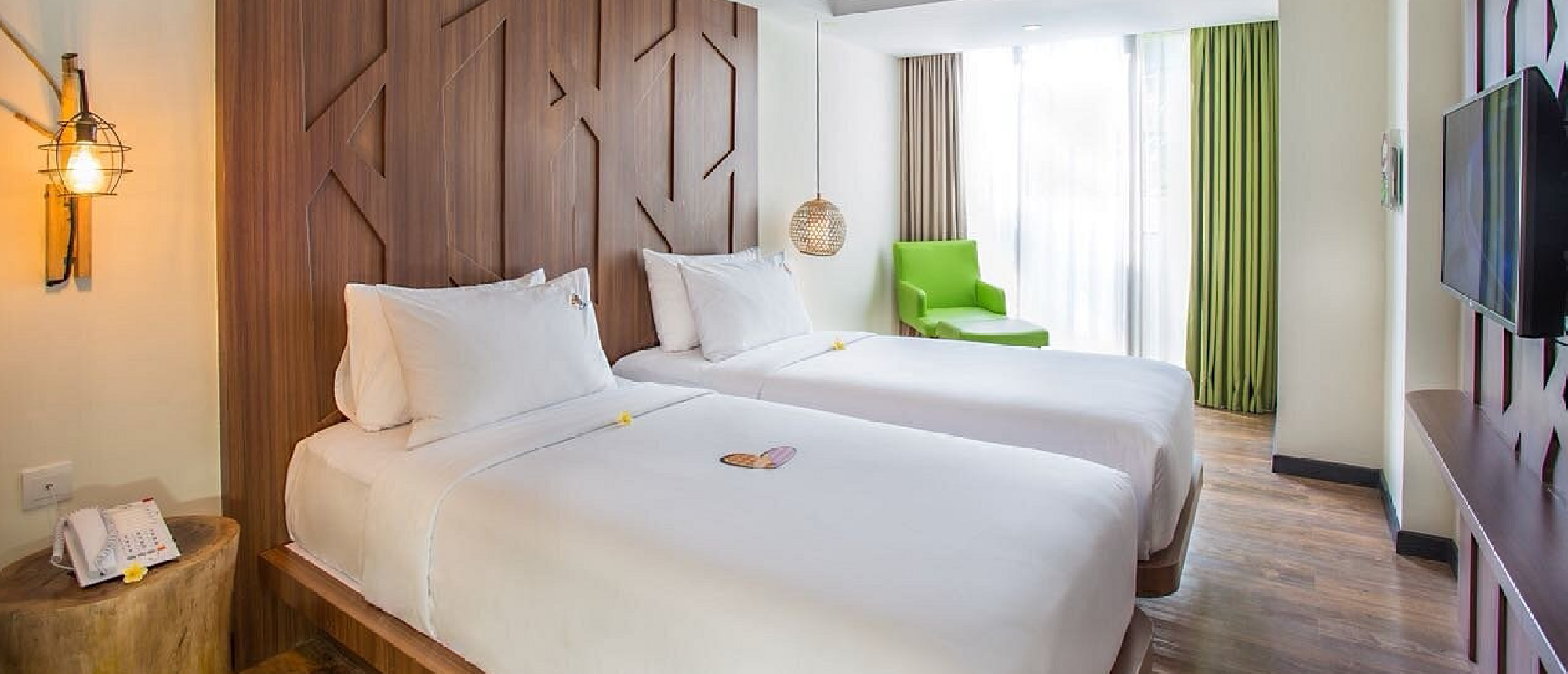 A contemporary hotel room with two single beds, white bedding, and a decorative wooden wall panel.