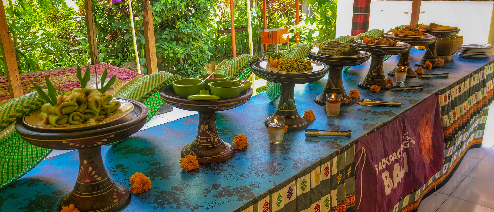 A long table displaying traditional Balinese dishes and offerings in an outdoor setting in Bali.