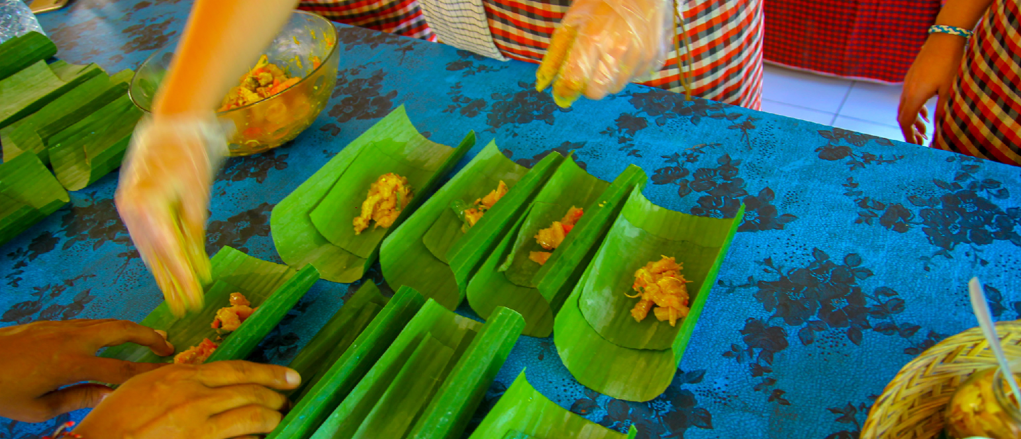 Hands preparing traditional Balinese food in banana leaves during a cooking class in Ubud.