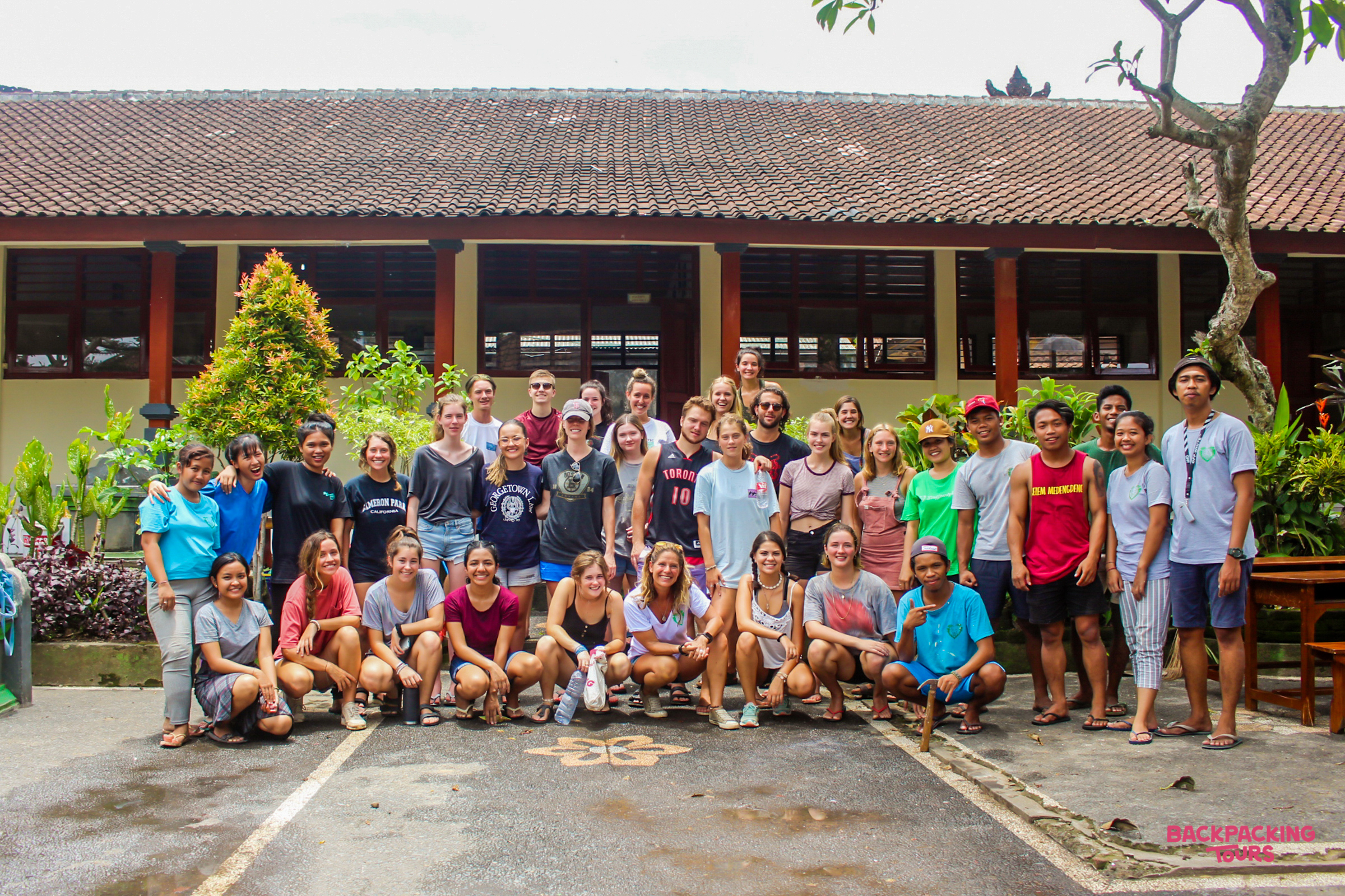 A large group of happy volunteers and local staff pose together in front of a building in Bali.