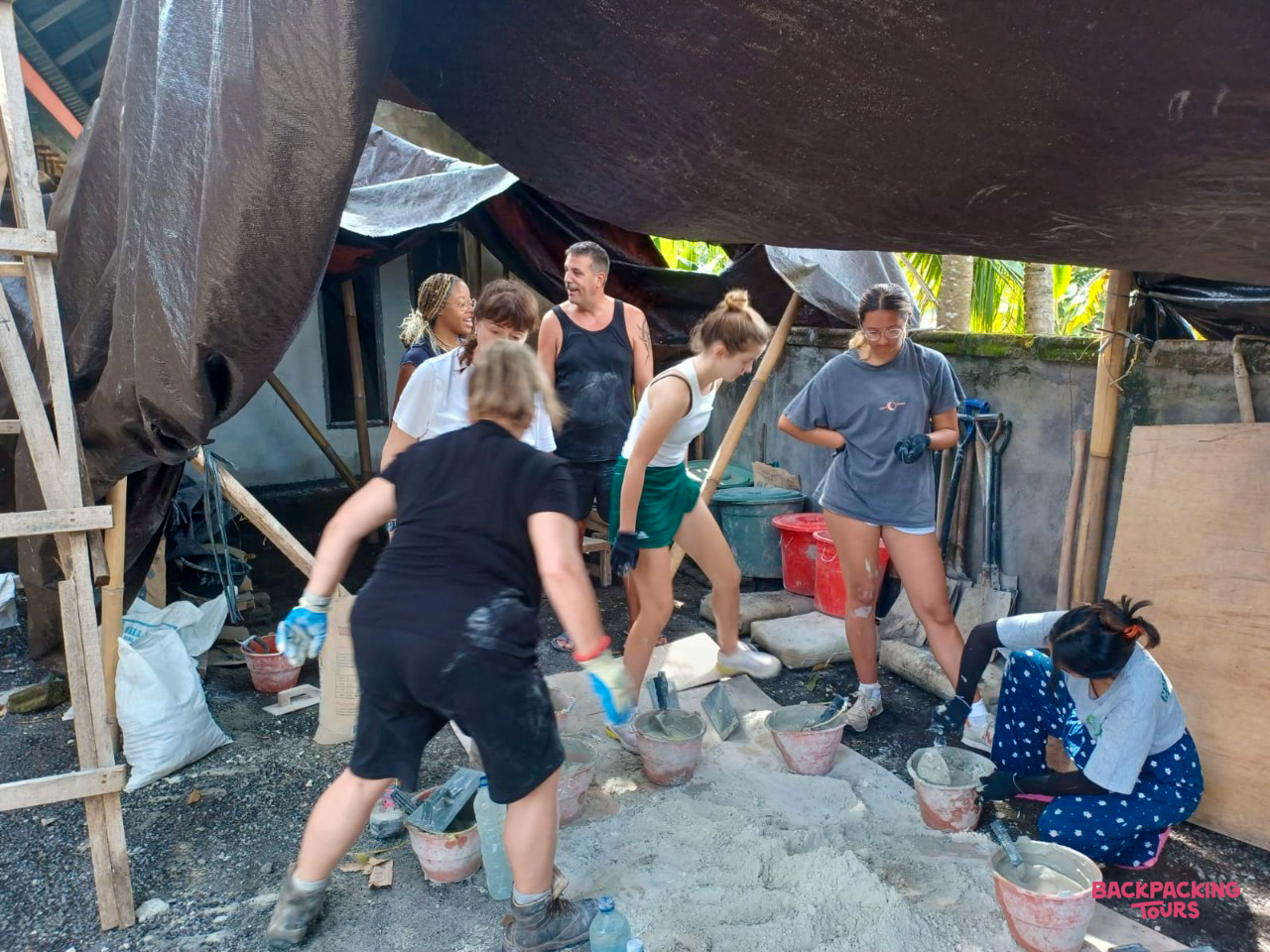A group of volunteers mixing cement by hand for a construction project in Bali.