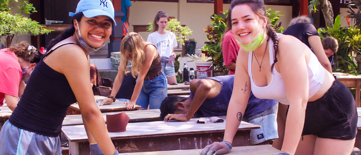 Happy volunteers sanding wooden surfaces during an outdoor community renovation project.