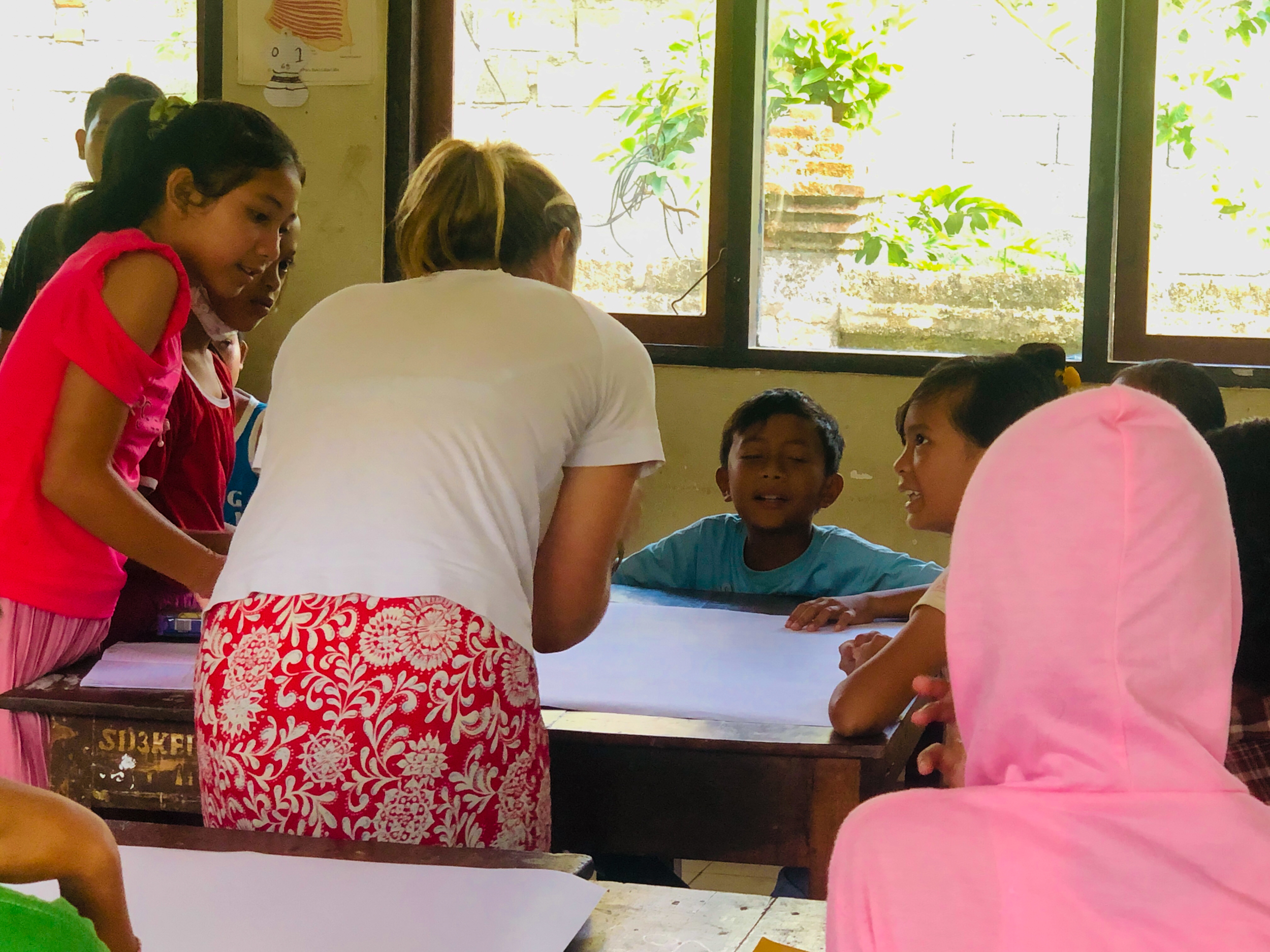 An adult volunteer leads an engaging educational activity with local children in Bali.
