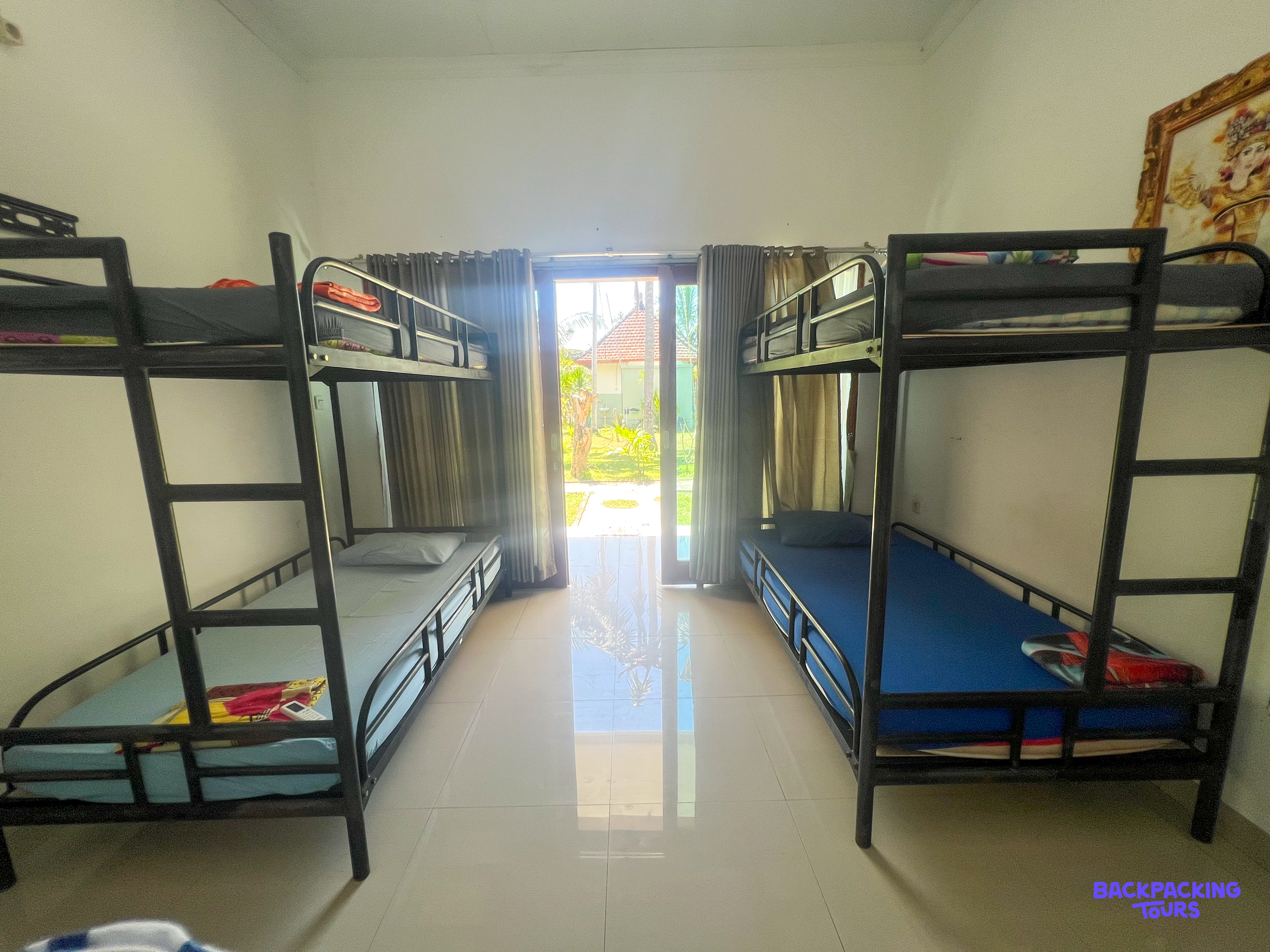 Bright dormitory room in Nusa Penida with four bunk beds, offering a sunny view of the garden.