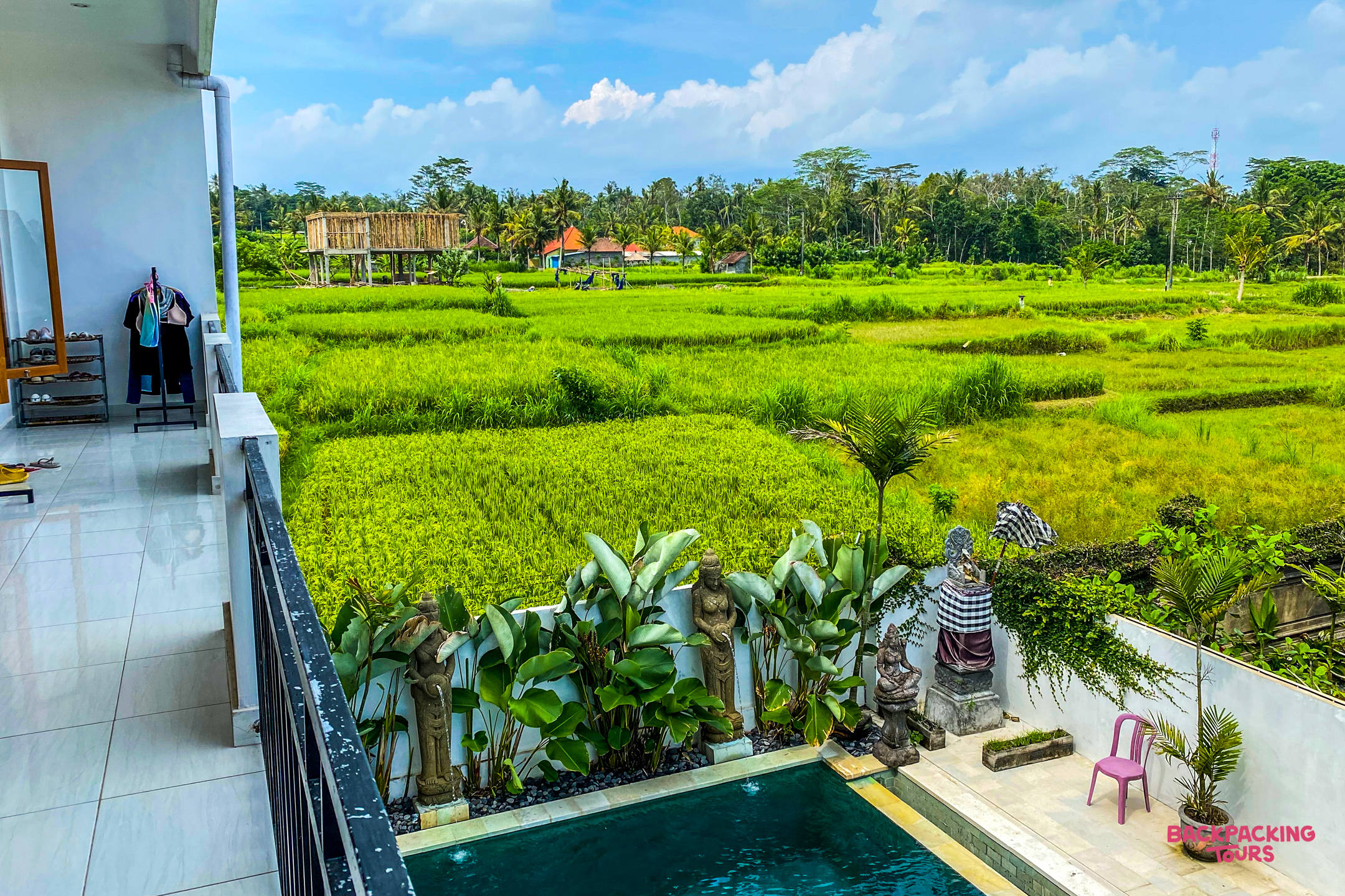 Relaxing view from a balcony overlooking a private pool and vibrant green rice fields in Bali.