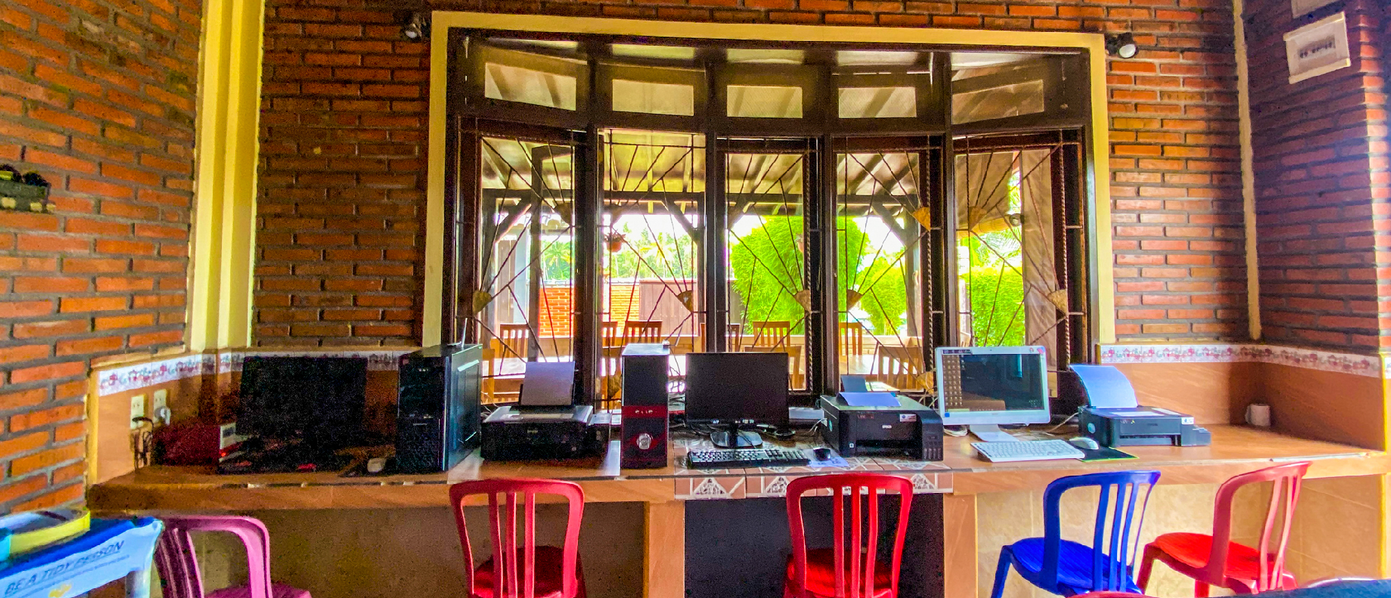 A welcoming common area with computers and bright chairs, offering views of lush outdoor greenery.