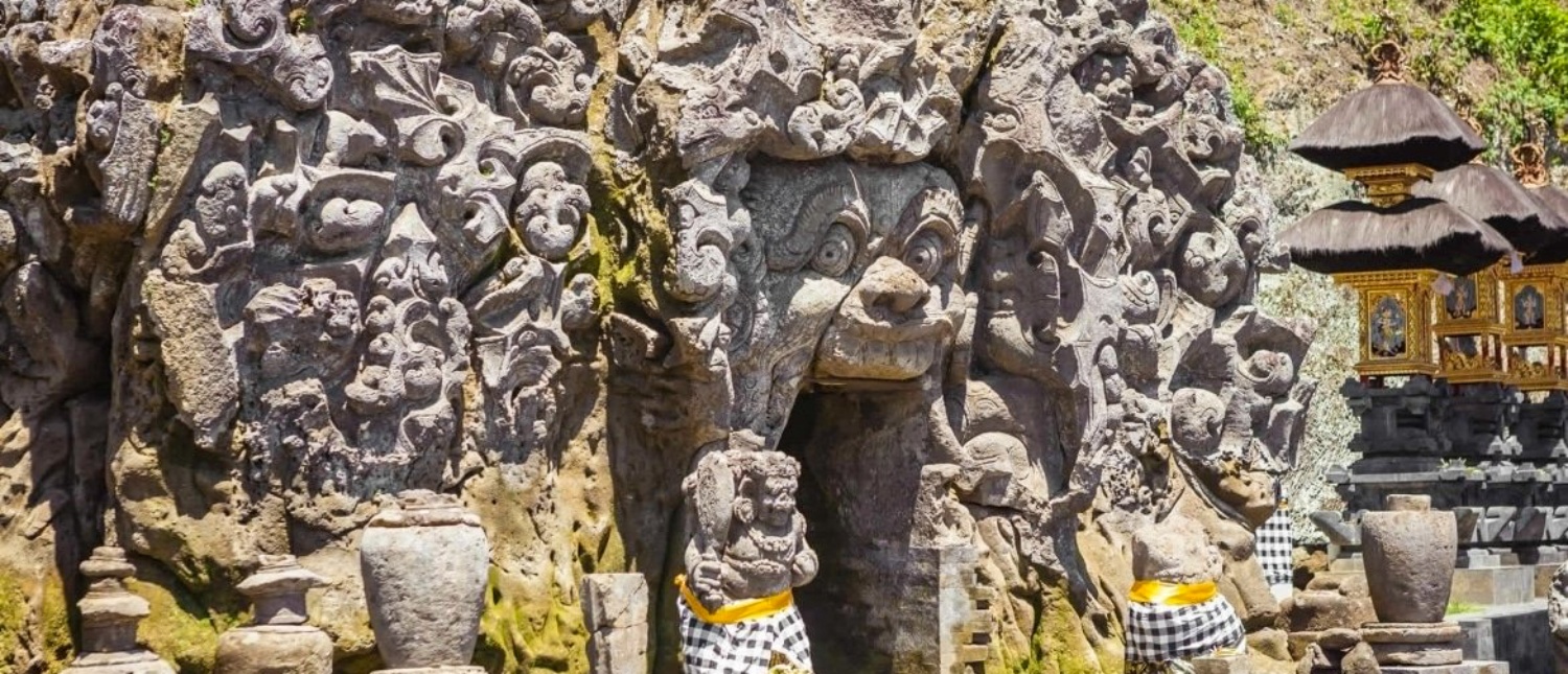 Detailed stone carvings of a demon mouth entrance at the ancient Goa Gajah temple in Bali.