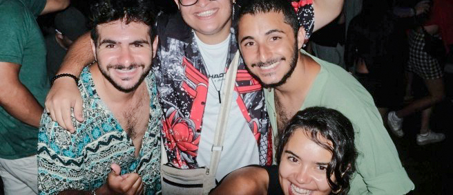 Four happy friends smiling and posing together at a lively night celebration in São Paulo.