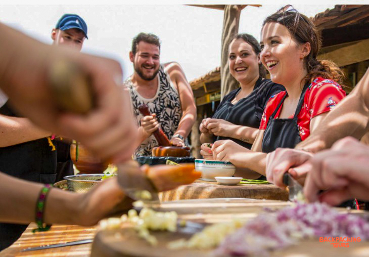 Happy travelers learn to cook Cambodian dishes during a fun cooking class in Kampot.