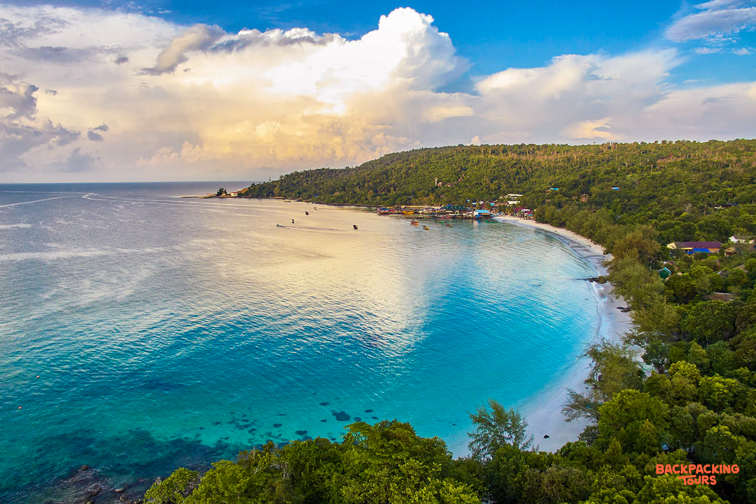 Stunning aerial view of Koh Rong island's serene turquoise bay, white sand beach, and green hills.