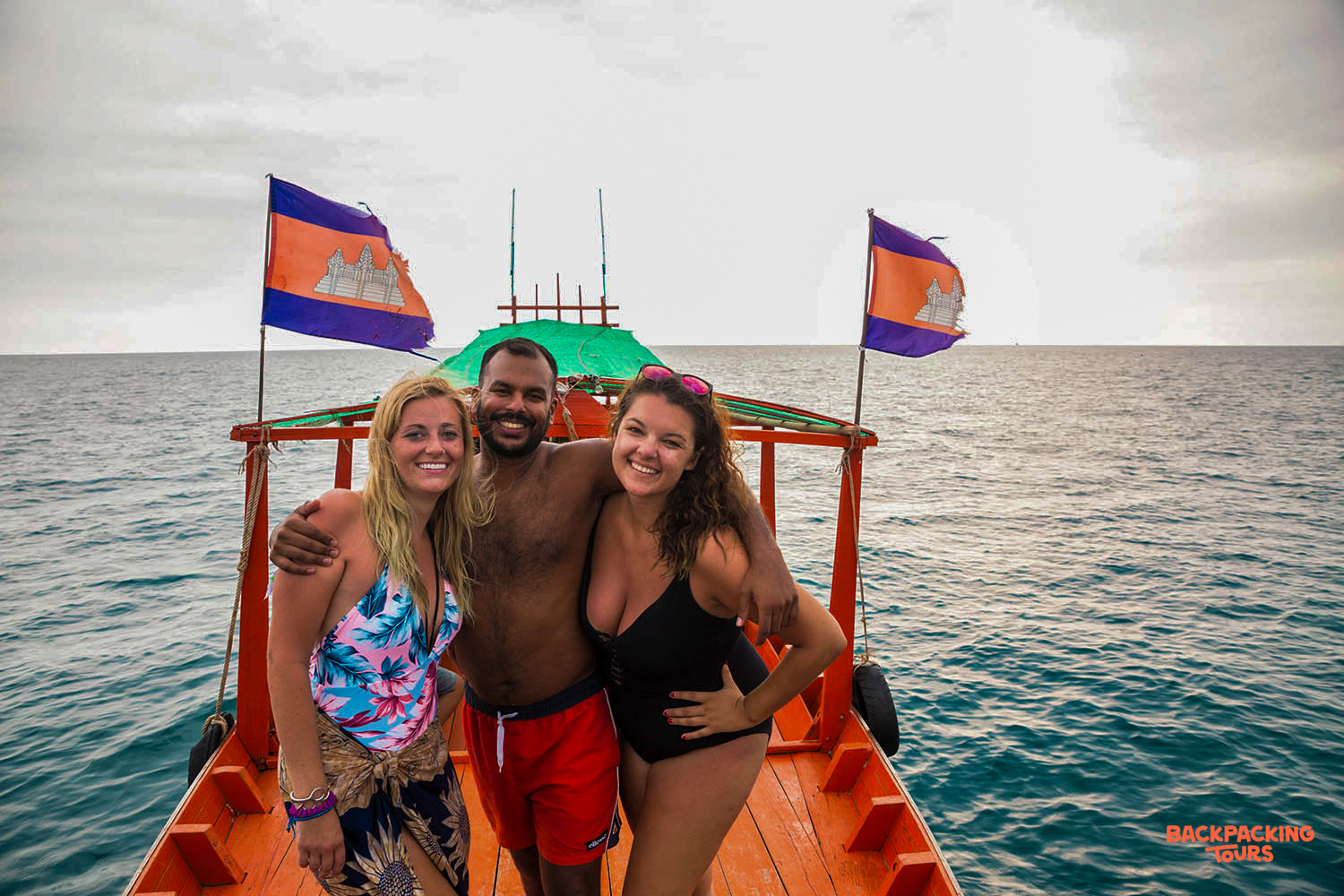Three happy backpackers pose on a boat trip in Koh Rong, enjoying the ocean views.