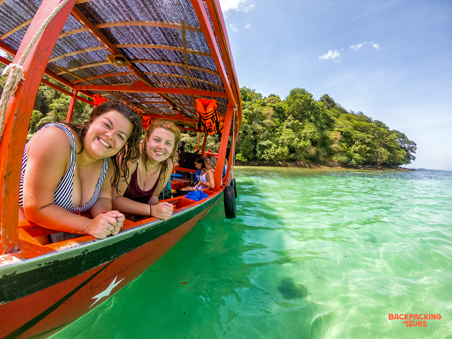 Two smiling women enjoy a sunny boat trip on the clear turquoise waters of Koh Rong.