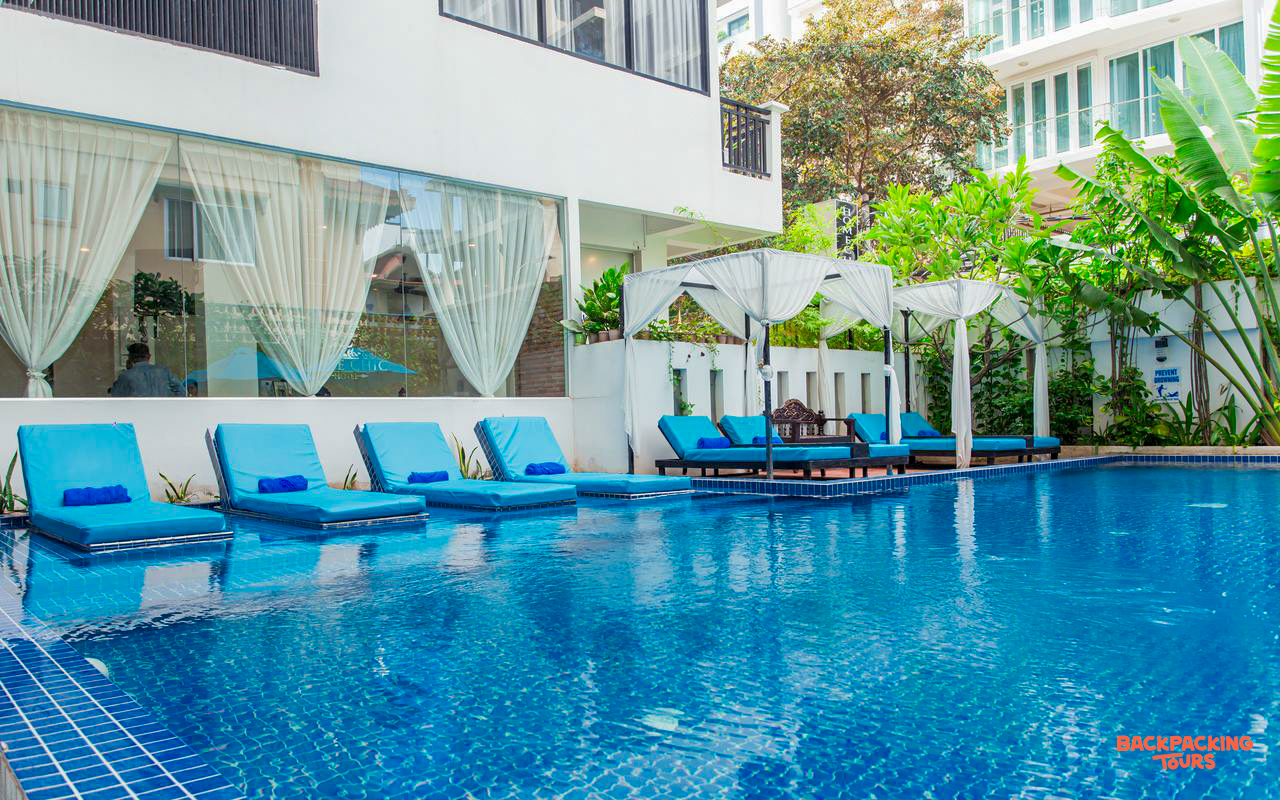An inviting swimming pool at a modern hotel in Phnom Penh, with comfortable blue sun loungers.