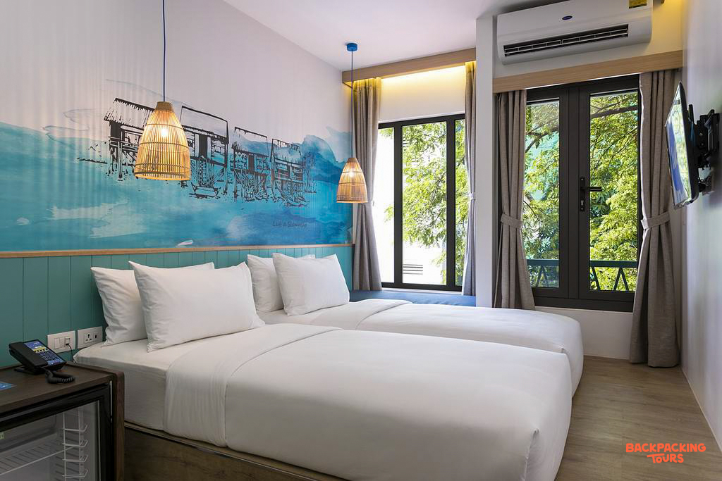 Bright and clean twin room in a Siem Reap hostel, decorated with a floating village mural.