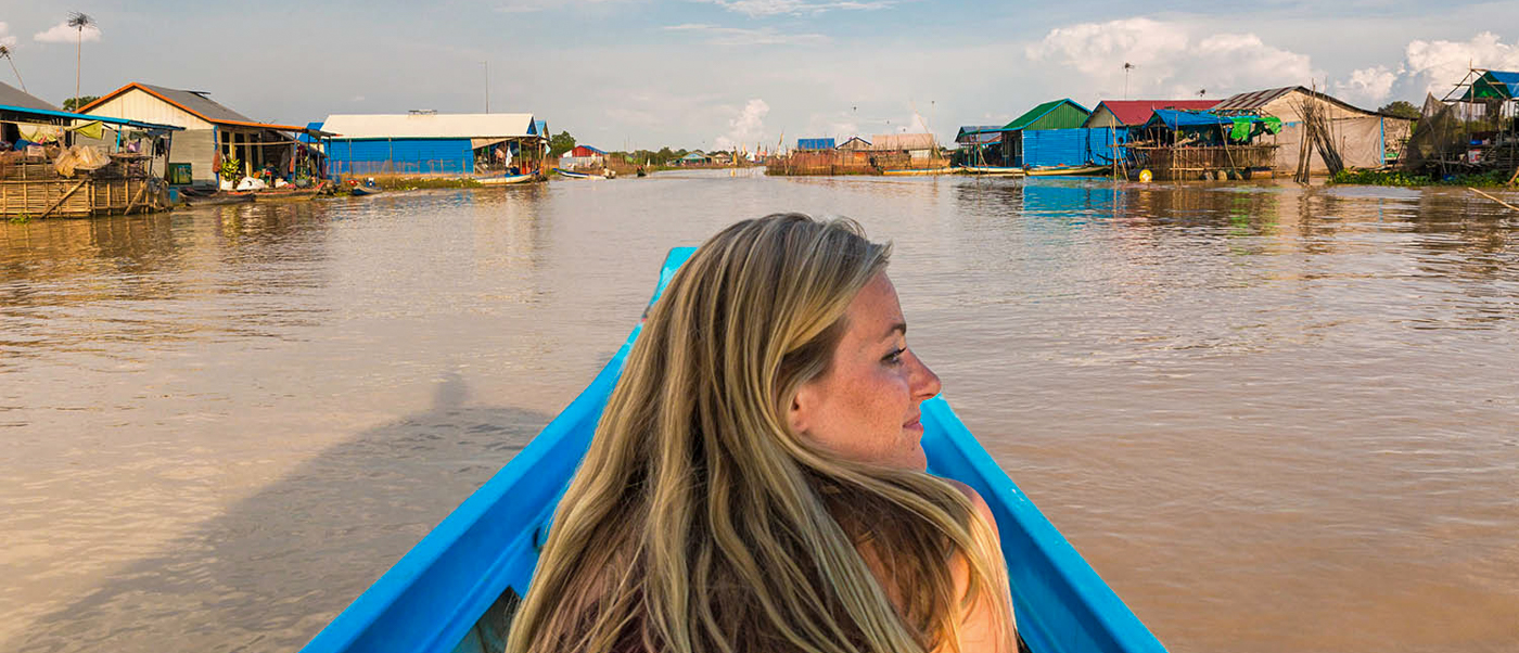 Blonde woman smiling while boating through traditional floating villages near Siem Reap.
