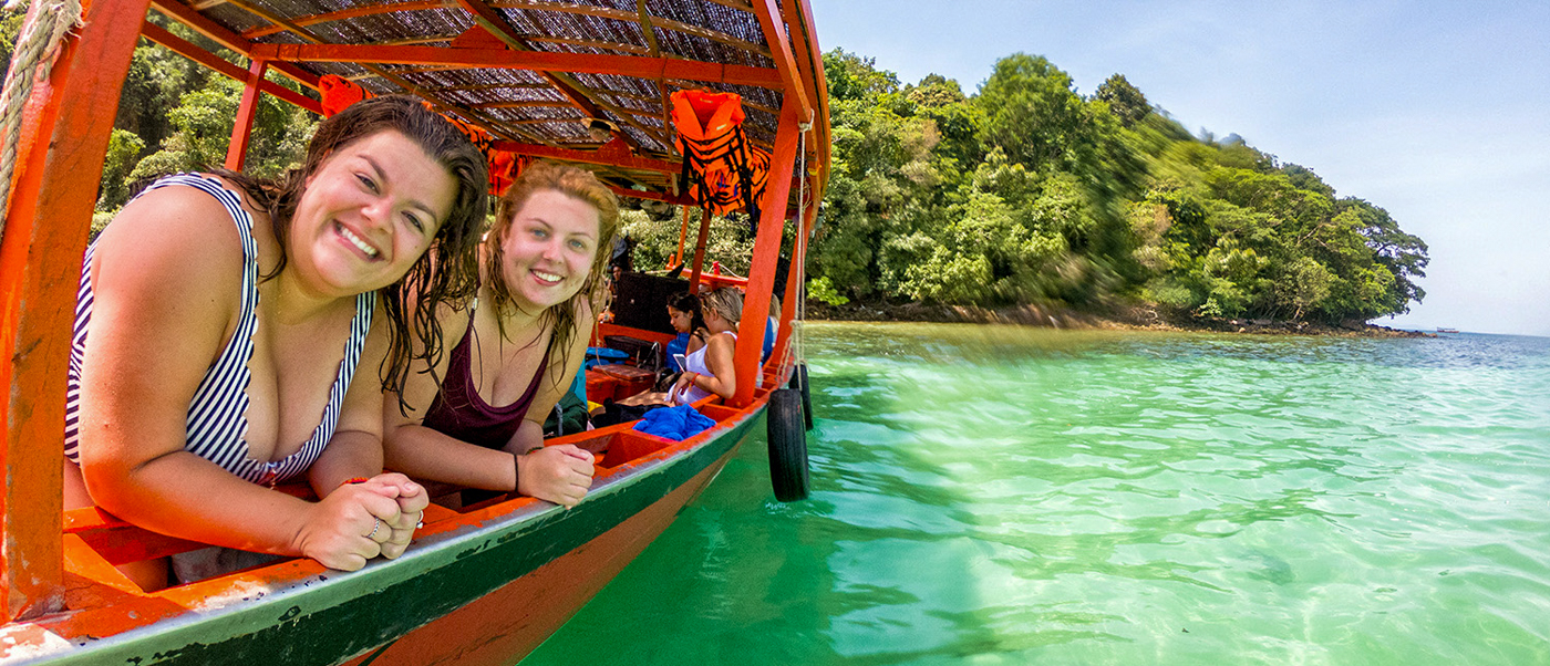 Two smiling women enjoy a private long-tail boat ride on the clear waters of Koh Rong.