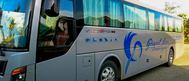 A modern Giant Ibis sleeper bus, silver with blue branding, parked outdoors on a sunny day.