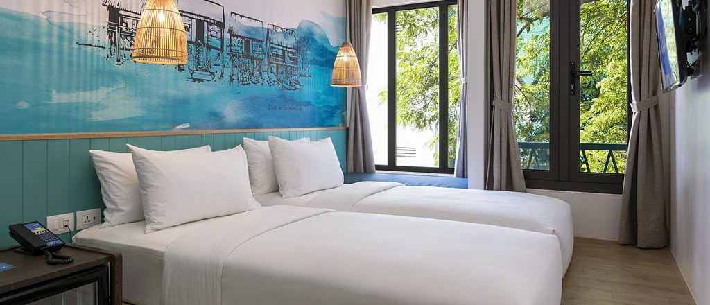Comfortable twin room in a Siem Reap hostel, decorated with a blue mural and natural light.