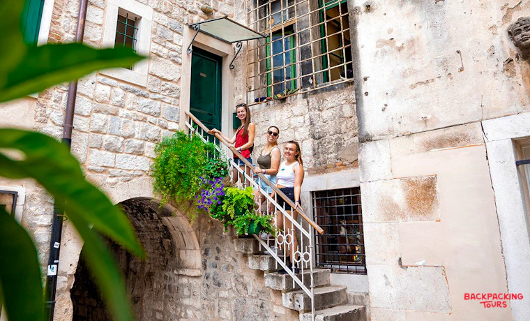 Three friends exploring the charming old town of Split, posing on a beautiful stone staircase.