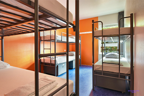 A dorm room with metal bunk beds and an orange wall at the Amsterdam hostel