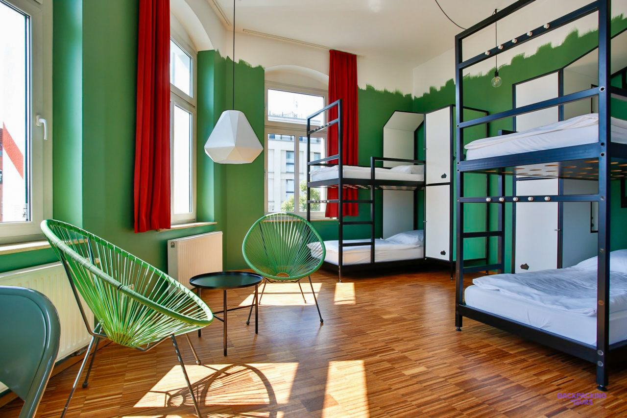 A dorm room with bunk beds, a green wall and a hanging lamp at the Berlin hostel