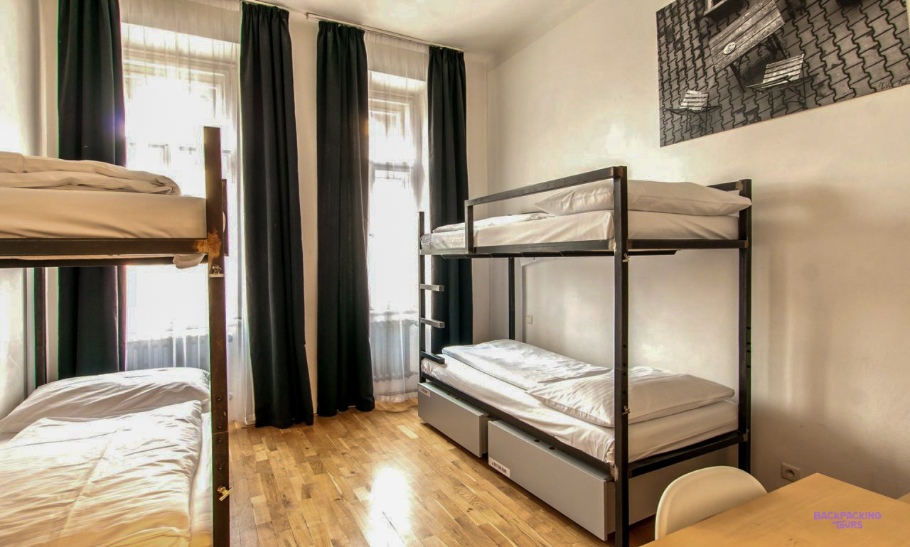 Metal bunk beds and a single bed in a bright dorm room at the Prague hostel