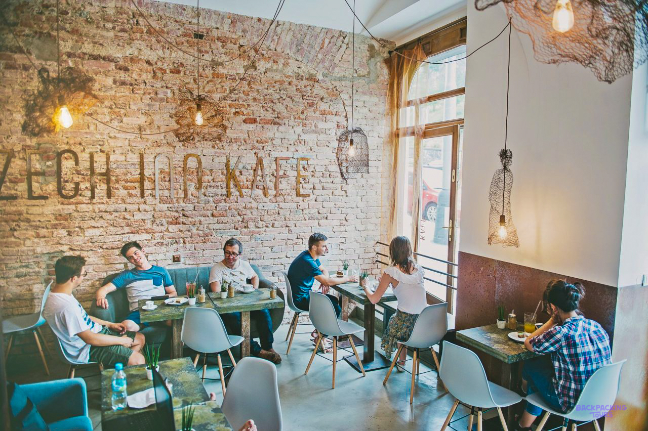 Travellers sitting at tables in the café of the Prague hostel