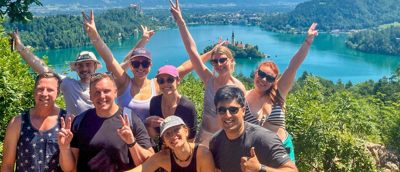 A group of travellers cheers at a viewpoint high above Lake Bled.