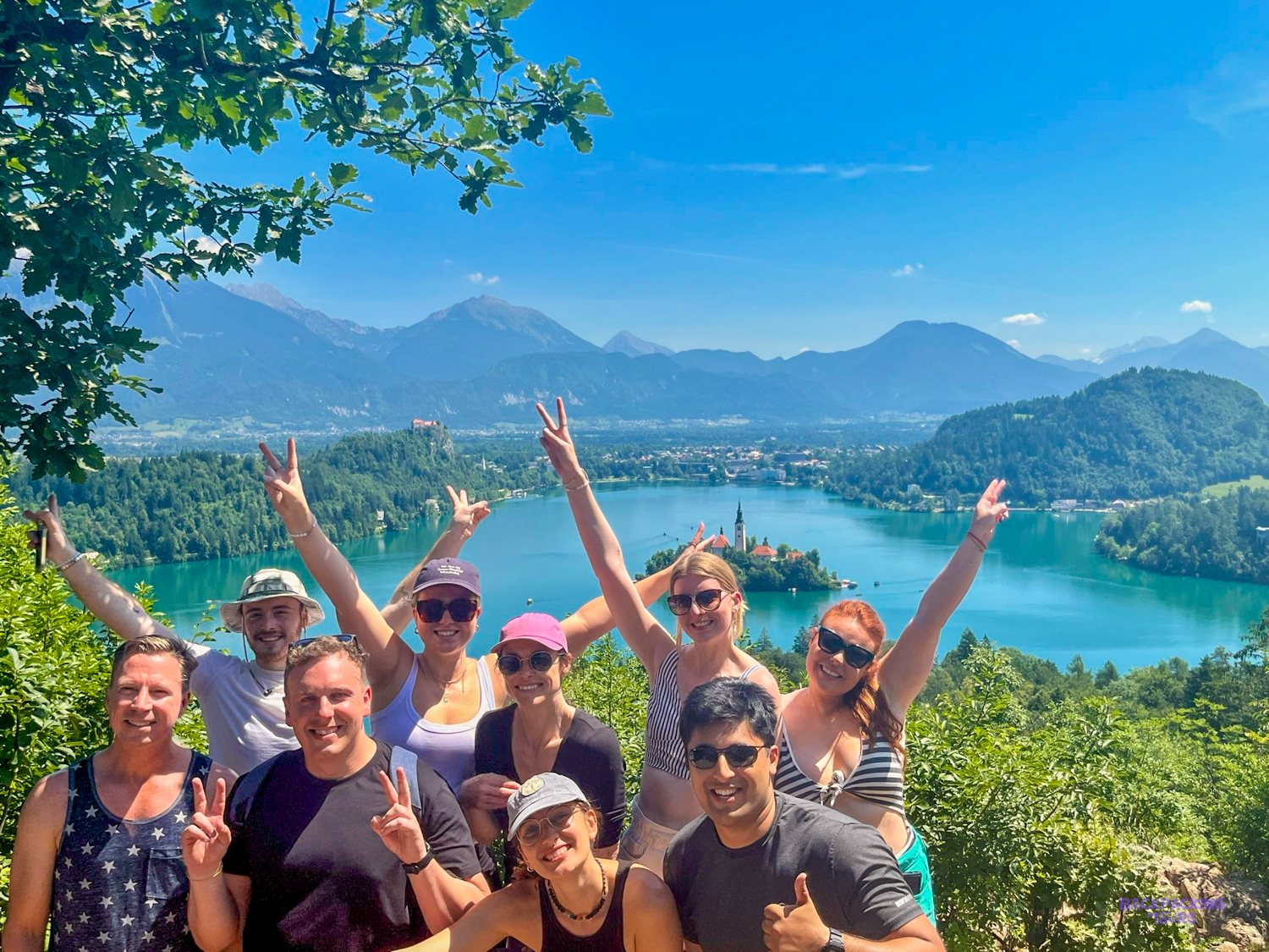 A group of travellers cheers at a viewpoint high above Lake Bled.