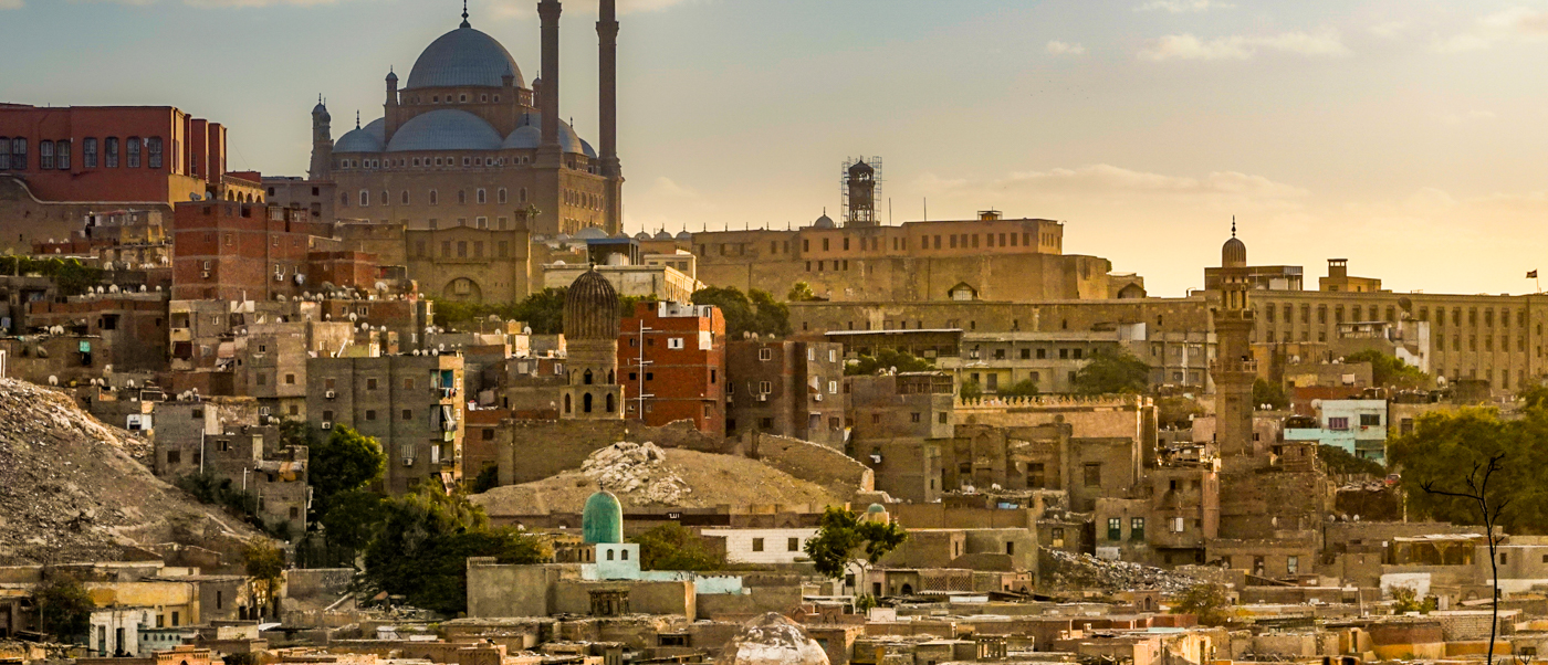 Historic Cairo cityscape at golden hour, with the Muhammad Ali Mosque and Citadel overlooking the city.