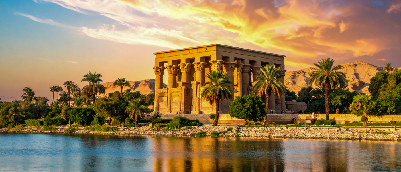 The ancient Philae Temple in Aswan, Egypt, beautifully reflected in the Nile at sunset.