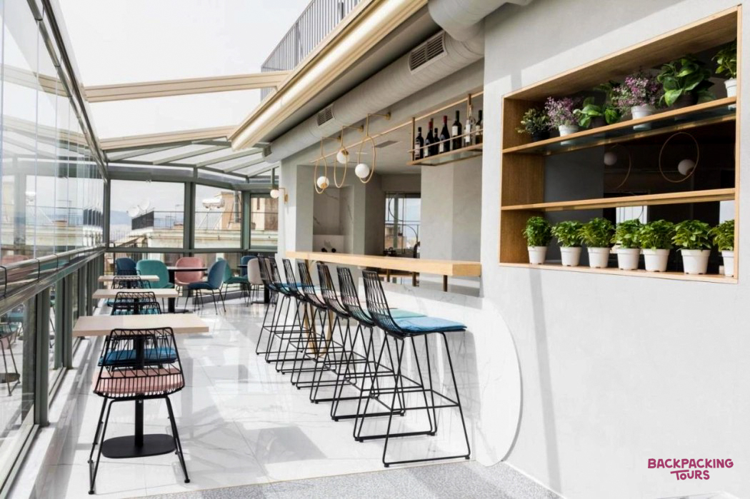 Enjoying the modern rooftop bar in Athens, featuring a glass ceiling and stylish seating.